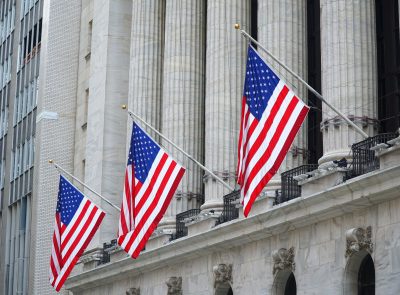 image of 3 American flags attached to a building with multiple columns