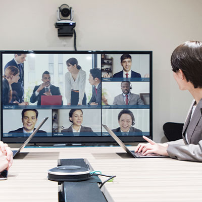 Multiple people on a television in a meeting room, in a live conference meeting