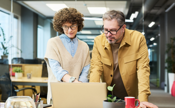 Man and woman watch a webinar in an office