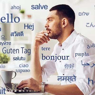 Man sitting at his computer, looking thoughtful with words floating around his head.