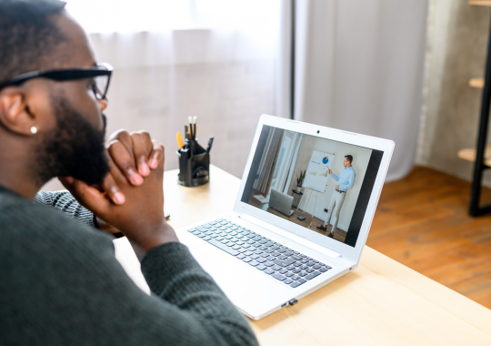 Man watching a video on a laptop with his hands folded