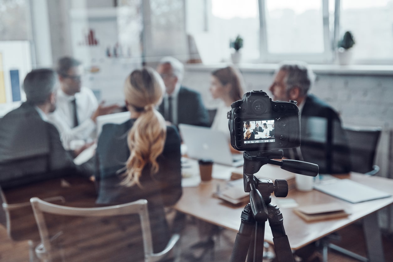 Group of people meeting in a conference room with camera recording them