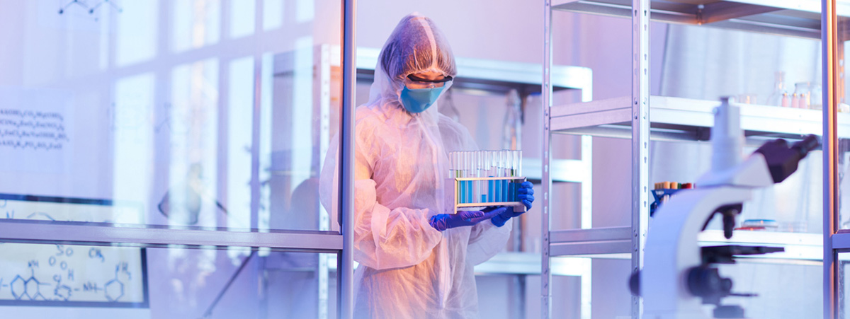 Chemist in protective costume carrying test tubes with samples she working at the medical laboratory