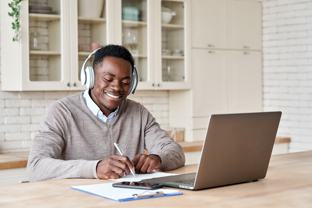 man looking happily at his laptop with headphones on
